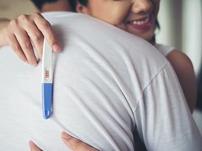 Happy couple smiling after positive pregnancy test result