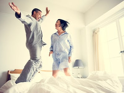 Young couple enjoying jumping on bed